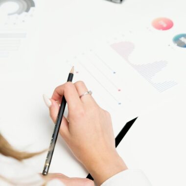 A woman reviews colorful financial charts with a pencil, focusing on growth and data analysis.
