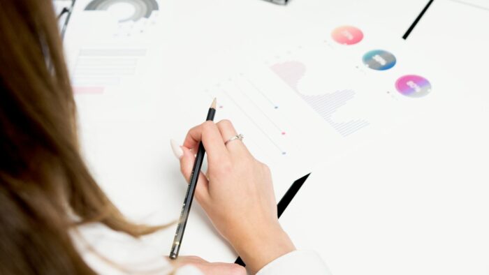 A woman reviews colorful financial charts with a pencil, focusing on growth and data analysis.