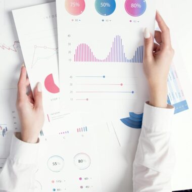Close-up of hands analyzing colorful business data reports in an office setting.