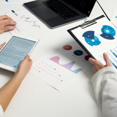 Team analyzing financial charts and digital reports during a business meeting.