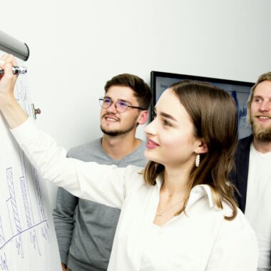 Three professionals collaborating on a business graph presentation in an office setting.